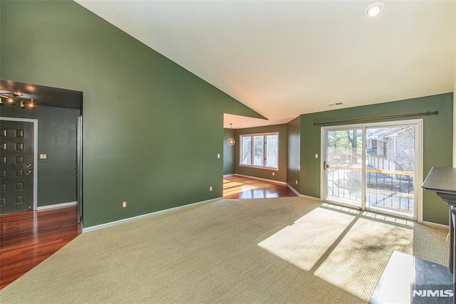 unfurnished living room with carpet floors and vaulted ceiling