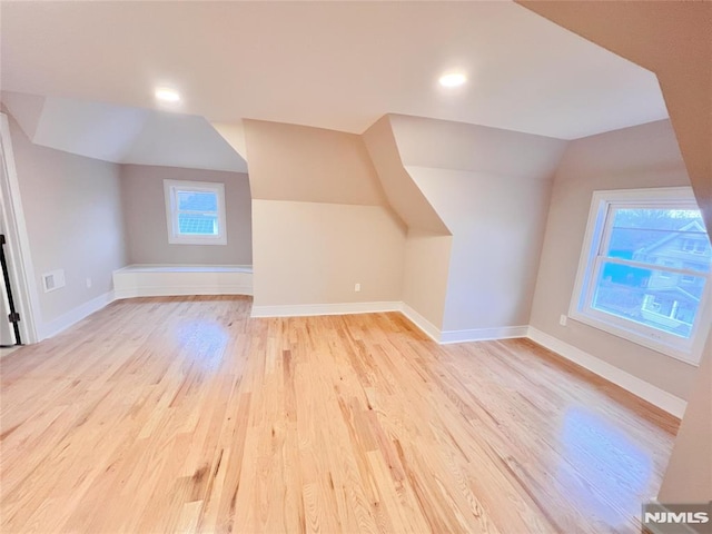 additional living space featuring vaulted ceiling and light wood-type flooring