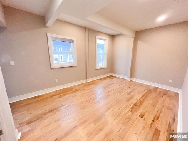 interior space with beam ceiling and light hardwood / wood-style flooring