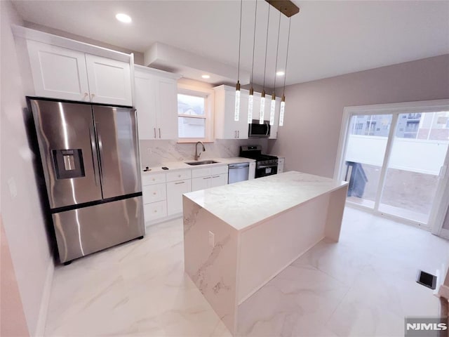 kitchen with a center island, sink, hanging light fixtures, appliances with stainless steel finishes, and white cabinets