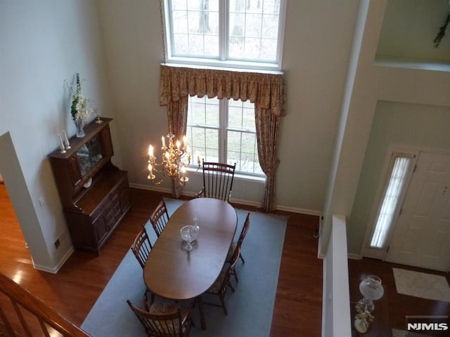 dining space with a high ceiling, dark hardwood / wood-style flooring, and a notable chandelier