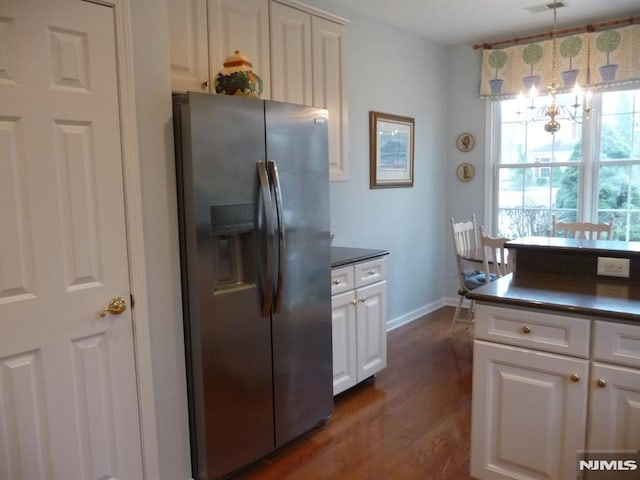 kitchen with pendant lighting, stainless steel fridge, white cabinetry, dark hardwood / wood-style floors, and a chandelier