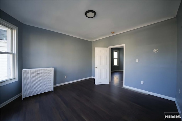 spare room with plenty of natural light and dark hardwood / wood-style floors