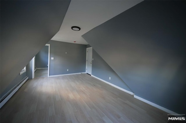 bonus room with light wood-type flooring, baseboard heating, and lofted ceiling