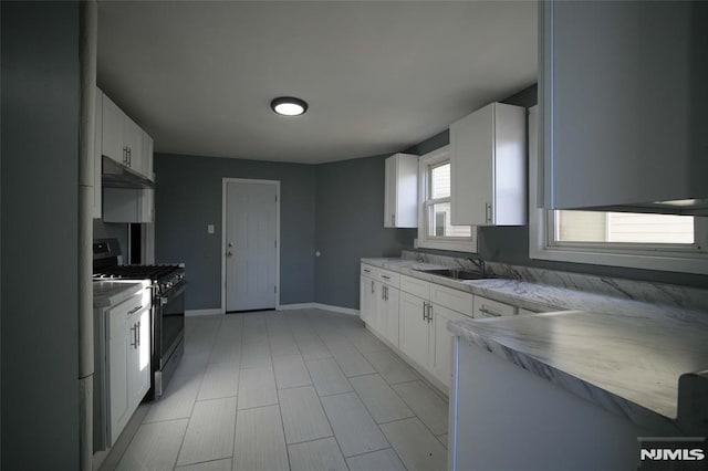 kitchen with range hood, white cabinetry, gas range oven, and sink