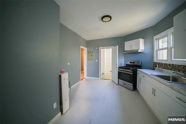 kitchen with backsplash, sink, gas stove, and white cabinetry