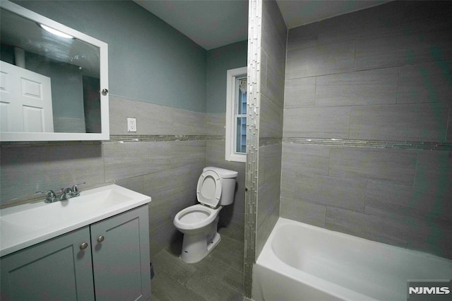 full bathroom featuring tile walls, toilet, vanity, and tiled shower / bath