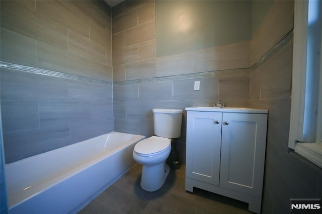 bathroom with toilet, vanity, and tile walls