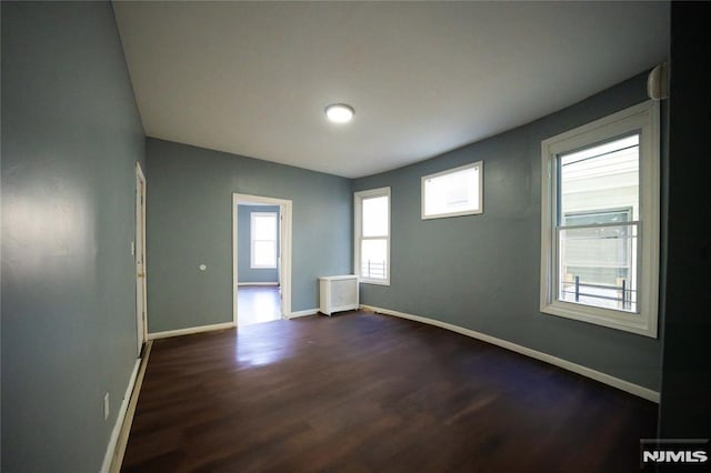 unfurnished room featuring dark hardwood / wood-style floors and a healthy amount of sunlight