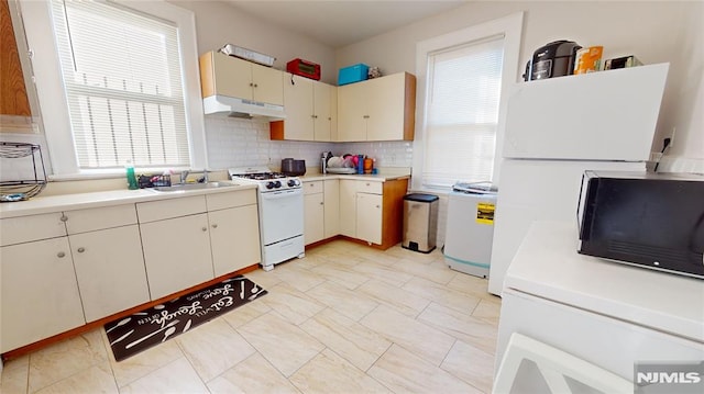 kitchen featuring decorative backsplash, sink, white appliances, and cream cabinets