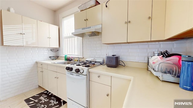 kitchen featuring white range with gas cooktop, light tile patterned flooring, and sink