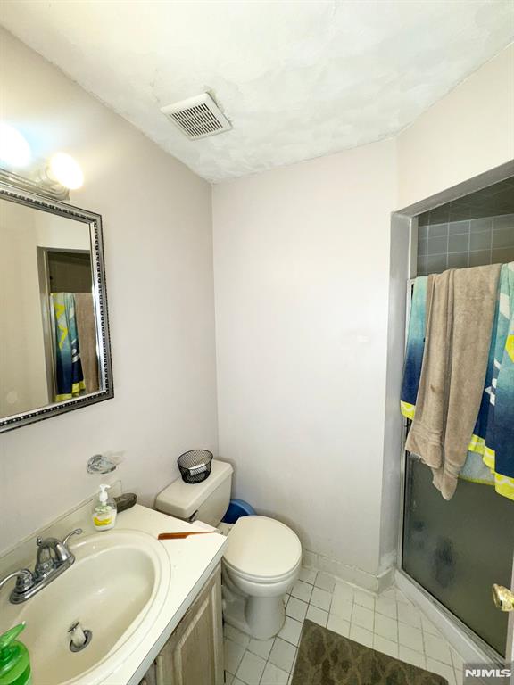 bathroom featuring toilet, an enclosed shower, and vanity