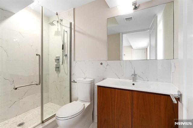 bathroom with toilet, tile walls, vanity, a shower with door, and decorative backsplash