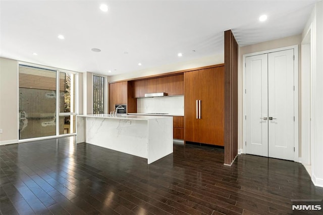 kitchen featuring sink, a breakfast bar, a center island with sink, and dark hardwood / wood-style flooring