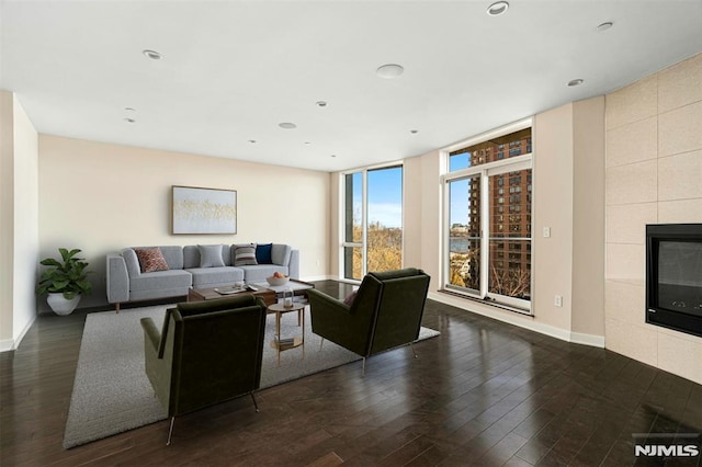 living room with floor to ceiling windows, dark hardwood / wood-style flooring, and a tile fireplace