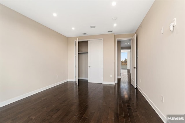 unfurnished bedroom with dark hardwood / wood-style floors and a closet