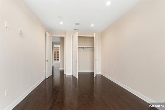 unfurnished bedroom featuring dark hardwood / wood-style flooring and a closet