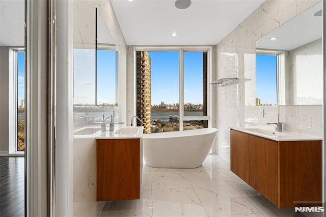 bathroom with a water view, vanity, and a bathing tub