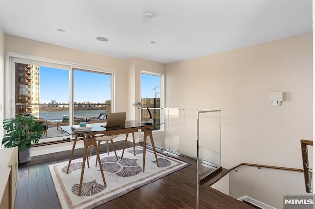 office with a water view and dark wood-type flooring