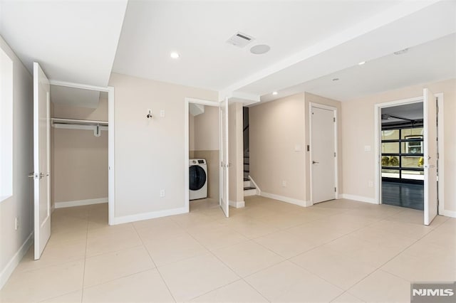 unfurnished bedroom with a walk in closet, washer / dryer, a closet, and light tile patterned floors