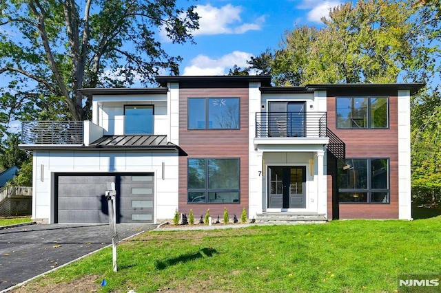 contemporary home with a garage, a front yard, and a balcony