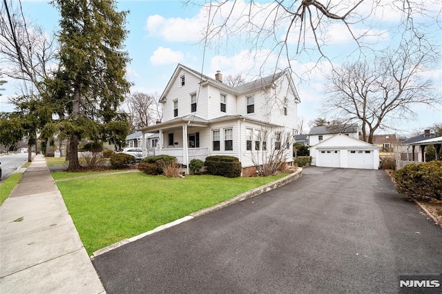 farmhouse-style home with a porch, an outbuilding, a garage, and a front lawn