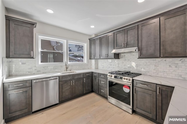 kitchen featuring sink, stainless steel appliances, light stone counters, and backsplash