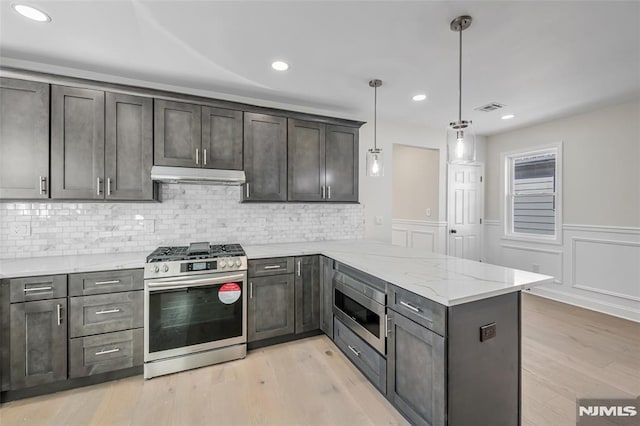 kitchen featuring kitchen peninsula, appliances with stainless steel finishes, decorative light fixtures, light wood-type flooring, and light stone counters