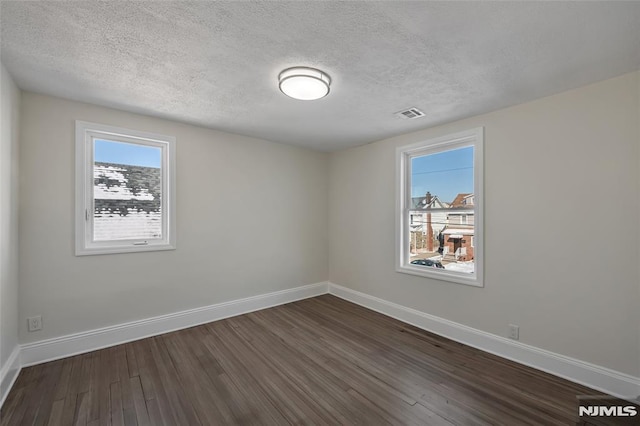 unfurnished room with dark wood-type flooring and a textured ceiling