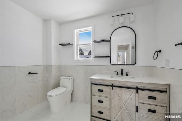 bathroom featuring toilet, tile patterned flooring, vanity, and tile walls