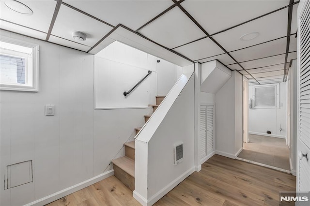 stairway featuring a paneled ceiling and hardwood / wood-style floors