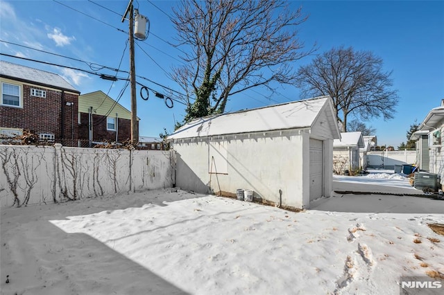 view of snowy exterior featuring an outbuilding and a garage