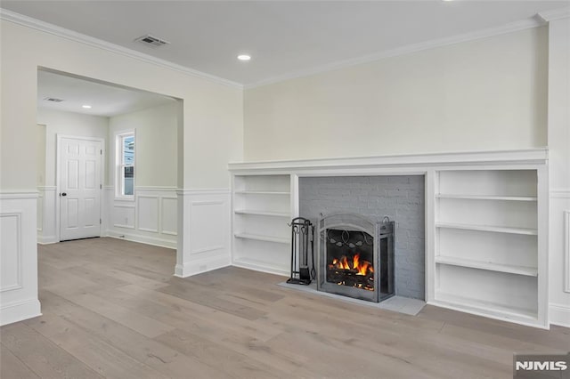 unfurnished living room featuring crown molding, light hardwood / wood-style floors, and a brick fireplace