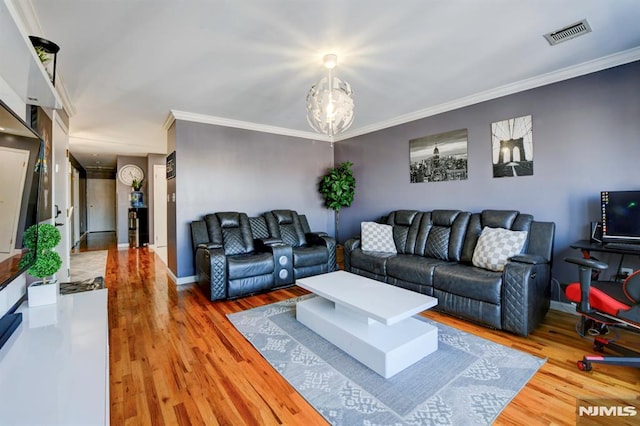 living room with ornamental molding, hardwood / wood-style floors, and a notable chandelier