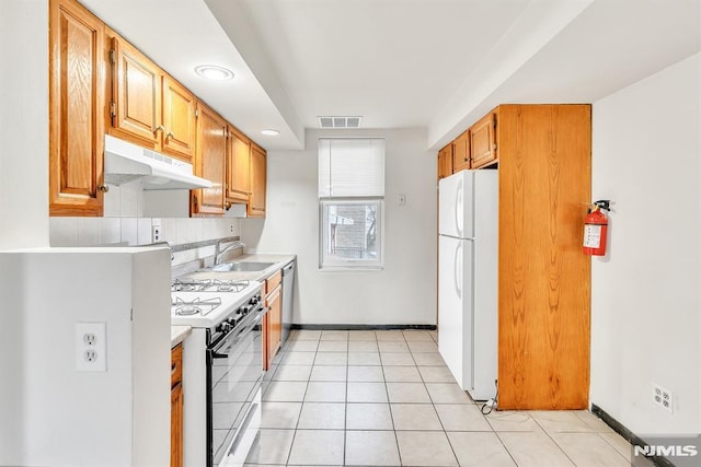 kitchen with light tile patterned flooring, sink, white appliances, and tasteful backsplash