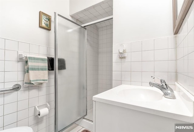 bathroom featuring tile walls, toilet, a shower with door, and vanity