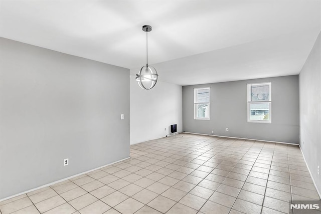 tiled spare room with a chandelier