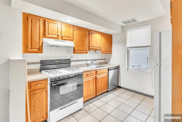 kitchen with light tile patterned floors, backsplash, sink, and white appliances