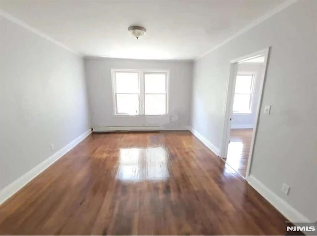 spare room with baseboard heating, ornamental molding, and dark hardwood / wood-style floors