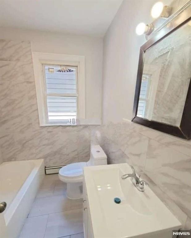 bathroom with toilet, vanity, tile walls, tile patterned flooring, and a bathtub