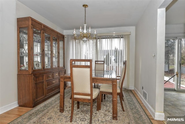 dining space with light hardwood / wood-style flooring and a notable chandelier