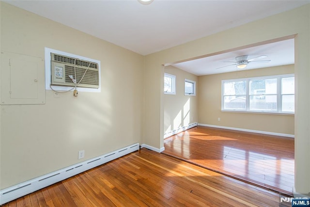 empty room featuring hardwood / wood-style flooring, a baseboard radiator, electric panel, and a wall unit AC