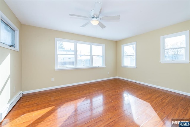 spare room with ceiling fan, baseboard heating, and light hardwood / wood-style flooring