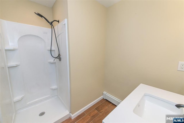 bathroom with sink, a shower, and a baseboard radiator