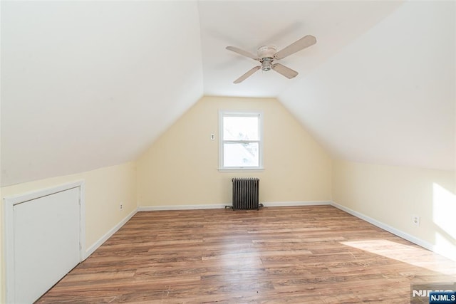 bonus room with hardwood / wood-style flooring, radiator, vaulted ceiling, and ceiling fan