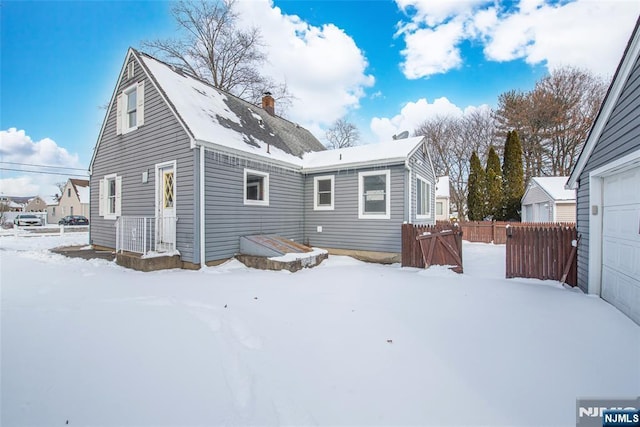 snow covered rear of property with a garage