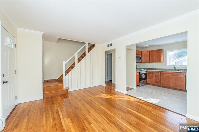 unfurnished living room with sink, light wood-type flooring, and ornamental molding