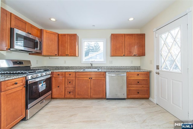 kitchen featuring light stone counters, sink, and stainless steel appliances