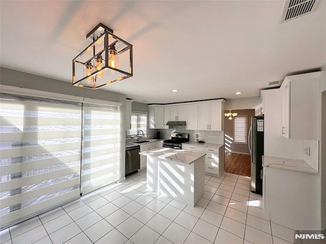 kitchen featuring light tile patterned floors, appliances with stainless steel finishes, a kitchen island, white cabinets, and sink