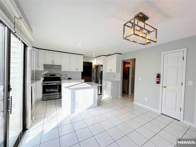 kitchen with tasteful backsplash, a kitchen island, stainless steel appliances, and white cabinetry